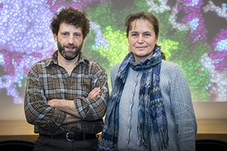 Two researchers standing in front of an animated picture, looking at camera