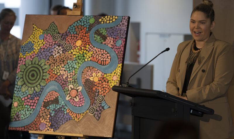 Aimee McCartney standing next to her custom-designed artwork