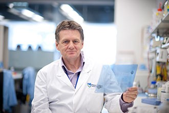 Professor Alan Cowman holding a transparency sheet in a lab