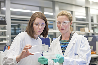 Two researchers in a laboratory, looking at an experiment