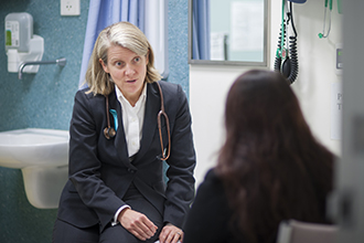 Associate Professor Clare Scott seated talking to a patient