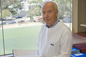 Professor Don Metcalf stands in his office with a lab notebook