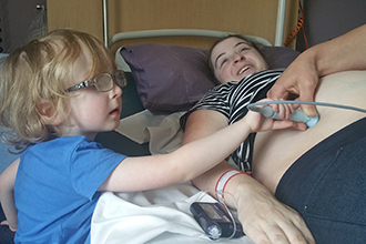 Woman having ultrasound with child sitting next to her