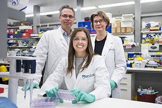 Three researchers in lab smiling at camera