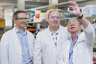 Associate Professor Guillaume Lessene, Dr Ueli Nachbur and Professor Andrew Lew looking at a vial in a laboratory