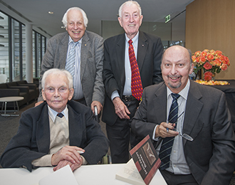 Group of four men, smiling, with book