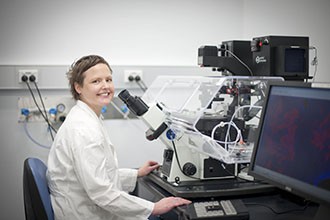 Dr Joanna Groom sitting in front a microscope