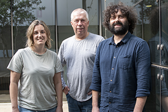 Three researchers standing outside a building