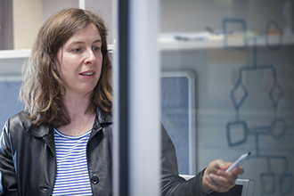 Associate Professor Melanie Bahlo standing and pointing at window with calculations written on it