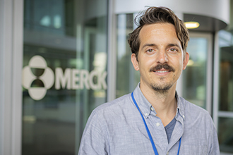 Smiling researcher in front of sign saying "Merck"