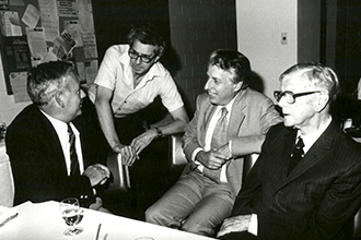 Black and white image of four men talking