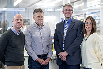 Four researchers standing and smiling at camera