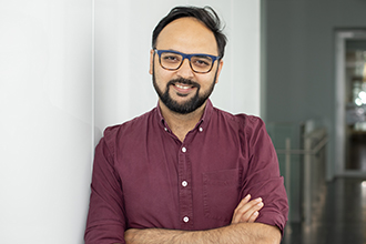 Man standing with folded arms, smiling at camera