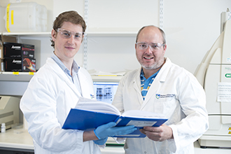 Researchers standing in laboratory, looking at camera