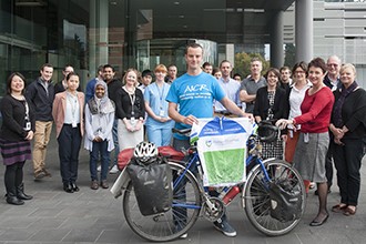 Chris Gruar holding bicycle in front of institute