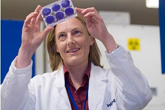 Gabrielle Belz holding microplate in lab