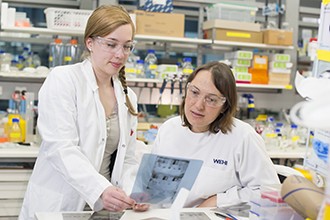 Maria Tanzer and Joan Hildebrand looking at gel photo in lab