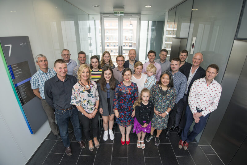 A group of men and women standing in a black tiled lobby