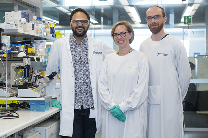 Three scientists smiling in a laboratory
