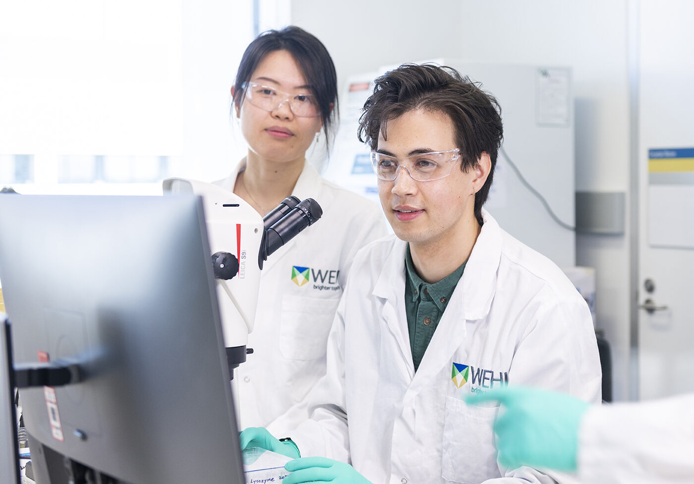 A student and supervisor working at a microscope
