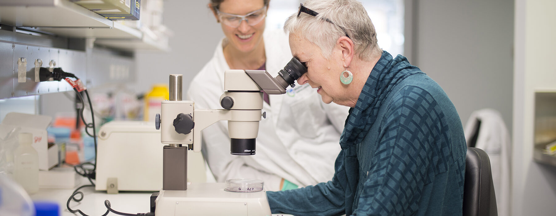 Clare Morgan and Roz Edmonds in WEHI lab looking through a microscope