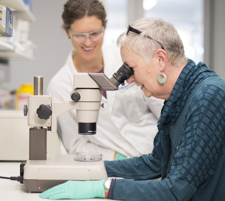 Clare Morgan and Roz Edmonds in WEHI lab looking through a microscope
