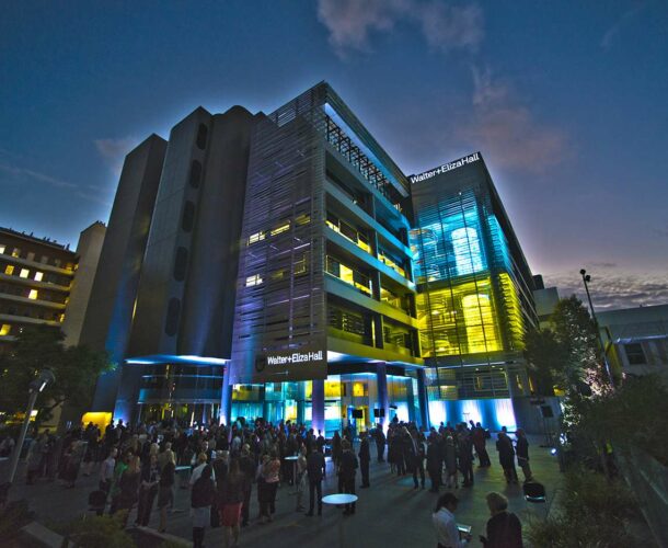 Staff and guests gather for the official launch of the centenary events program, lit by a new LED light curtain projecting scientific images to the public