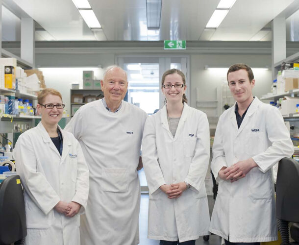 Two male and two female scientists in white coats posing in the Mason lab