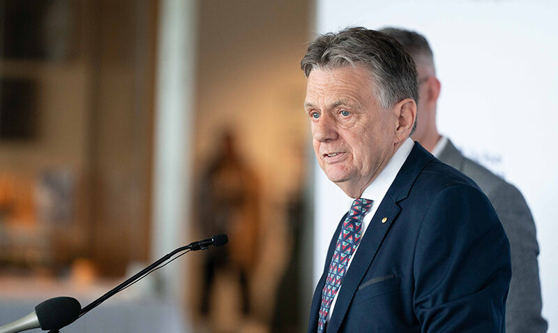Professor Alan Cowman is photographed speaking from a lectern with microphes.
