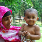 Woman wearing bright pink headscarf holding toddler