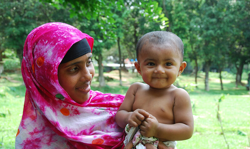 Woman wearing bright pink headscarf holding toddler