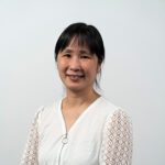Ellen Tsui posing for a portrait wearing a white long sleeve blouse