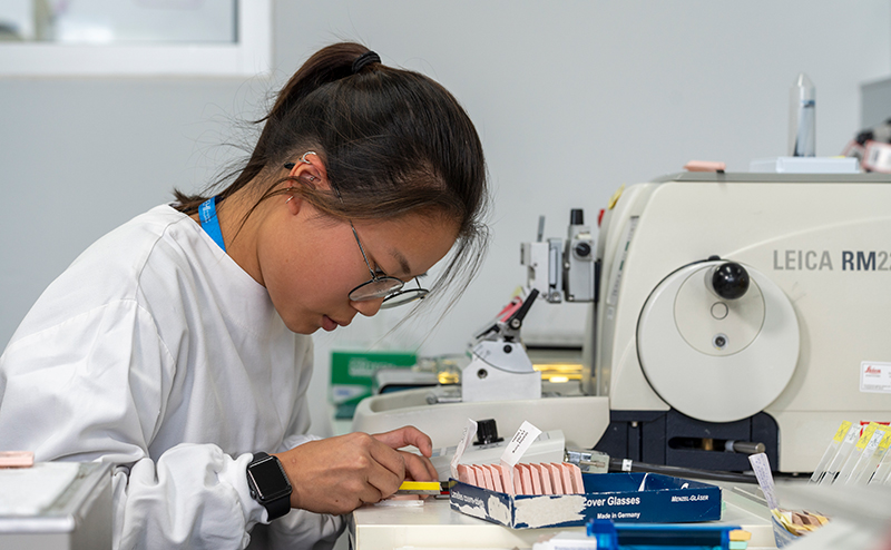 A female scientist wearing a lab coat preparing slides