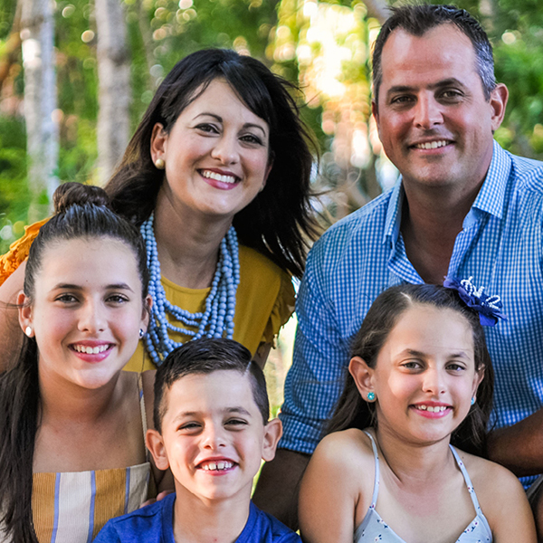 A family photo showing two parents and three young children, together in a forest setting