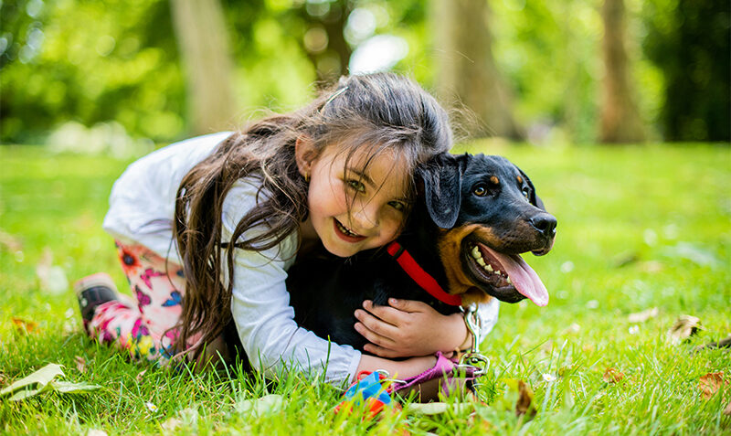 Photograph of a young girl hugging a dog