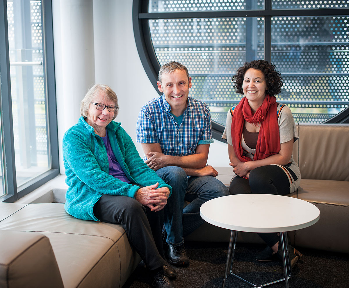 Two WEHI researchers are photographed sitting with a member of public