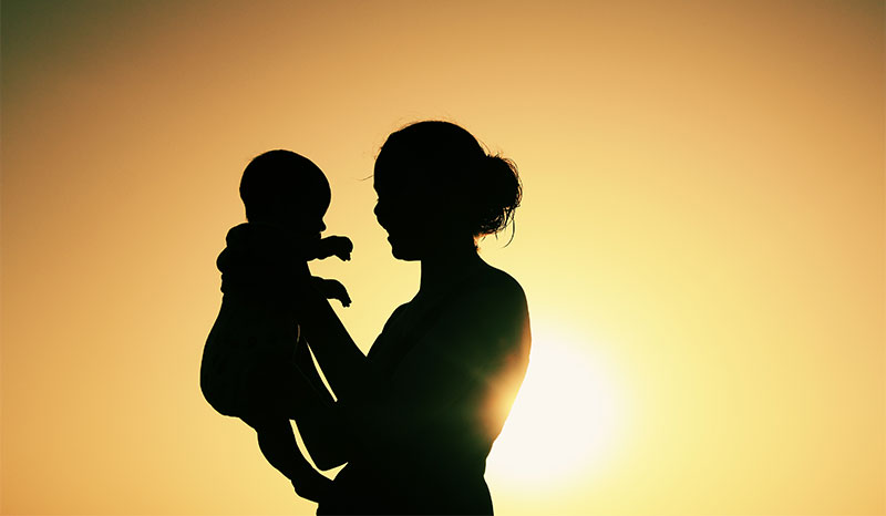 A woman holding a baby shown in silhouette