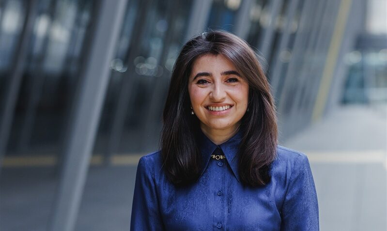 Photo of Dr Aysha Al-Ani standing outside a modern building