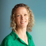 Portrait photo of Clare Parrish with a blurred green background