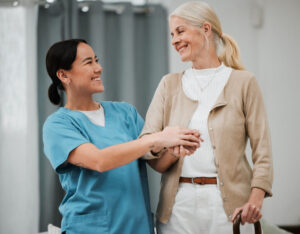 A carer is photographed supporting a woman using a walking stick